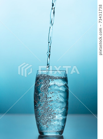 Fresh water pouring into a glass on the blue background 73431738