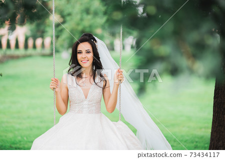 Beauty portrait of bride wearing fashion wedding dress with feathers with luxury delight make-up and hairstyle Beauty portrait of bride wearing fashion wedding dress with feathers with luxury delight make-up and hairstyle 73434117