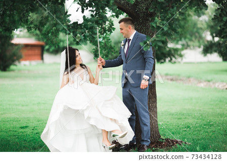 Man pushing his newlywed wife on a swing Man pushing his newlywed wife on a swing 73434128