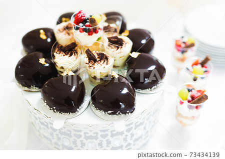 Delicious and tasty dessert table with cupcakes and shots at reception closeup Delicious and tasty dessert table with cupcakes and shots at reception closeup 73434139