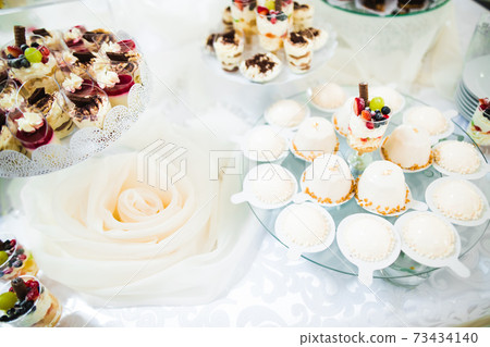 Delicious and tasty dessert table with cupcakes and shots at reception closeup Delicious and tasty dessert table with cupcakes and shots at reception closeup 73434140