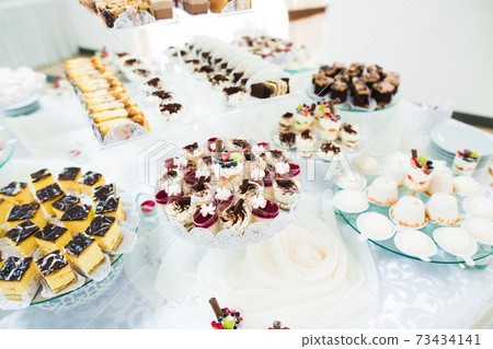 Delicious and tasty dessert table with cupcakes and shots at reception closeup Delicious and tasty dessert table with cupcakes and shots at reception closeup 73434141
