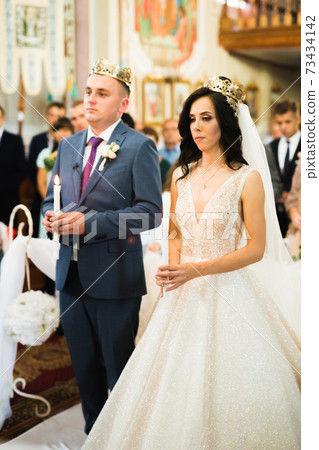 Bride and groom holding candles in church Bride and groom holding candles in church 73434142