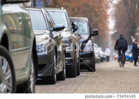 Cars parked in a row on a city street side. Cars parked in a row on a city street side. 73434145