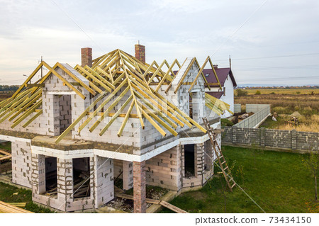 Aerial view of a private house with aerated concrete brick walls and wooden frame for future roof. 73434150