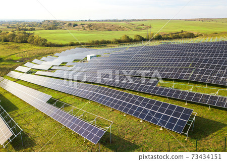 Aerial view of solar power plant under construction on green field. Assembling of electric panels for producing clean ecologic energy. Aerial view of solar power plant under construction on green field. Assembling of electric panels for producing clean ecologic energy. 73434151