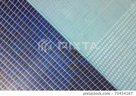 Aerial view of surface of blue photovoltaic solar panels mounted on building roof for producing clean ecological electricity. Production of renewable energy concept. 73434167