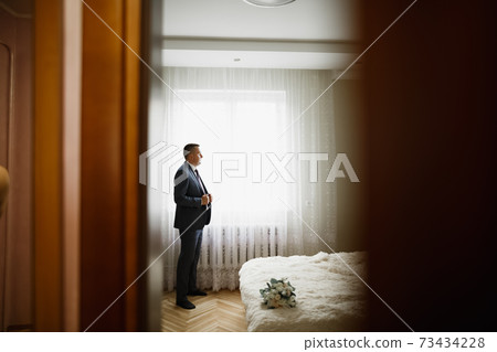 Grooms morning preparation. Handsome man getting dressed and preparing for the wedding Grooms morning preparation. Handsome man getting dressed and preparing for the wedding 73434228