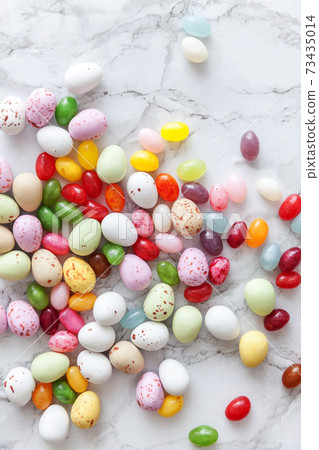 Happy Easter concept. Preparation for holiday. Easter candy chocolate eggs and jellybean sweets on trendy gray marble background. Simple minimalism flat lay top view copy space. 73435014