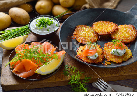 Crunchy potato pancakes with smoked salmon and chives quark served in an iron frying pan 73436650
