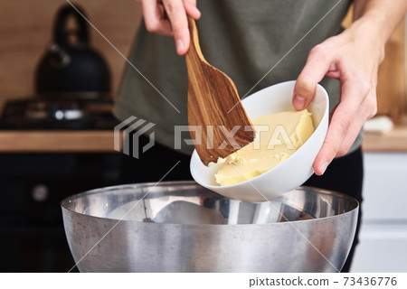 Hands put butter in a bowl. Cooking recipe Hands put butter in a bowl. Cooking recipe 73436776