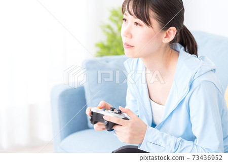 女人坐在沙發上，玩網絡遊戲 73436952