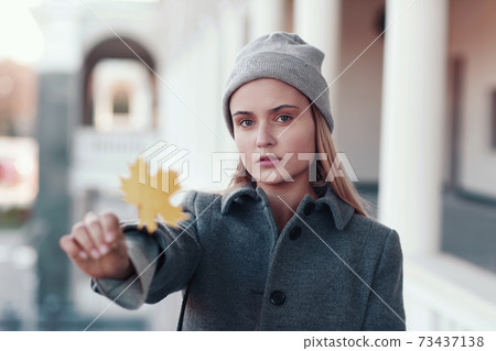 blond girl in knitted hat and coat with maple leaf close up portrait on city architecture background blond girl in knitted hat and coat with maple leaf close up portrait on city architecture background 73437138