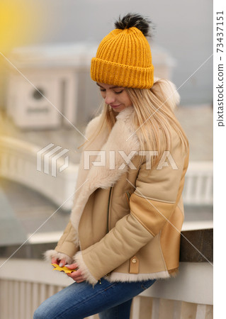 blond girl in knitted hat and coat with maple leaf close up portrait on city architecture background blond girl in knitted hat and coat with maple leaf close up portrait on city architecture background 73437151
