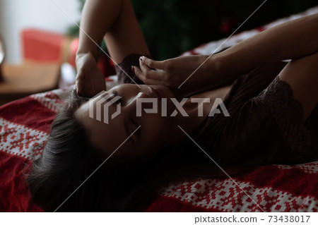 Alluring young lady relaxing on bed with closed eyes during Christmas holidays 73438017