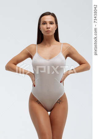 Slim woman in white bodysuit in studio Slim woman in white bodysuit in studio 73438042