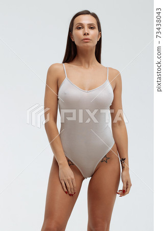 Slim woman in white bodysuit in studio Slim woman in white bodysuit in studio 73438043
