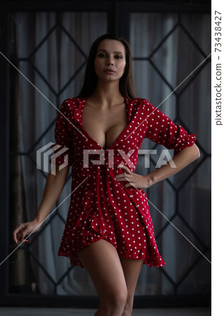 Stylish young woman in sexy dress standing with hand on waist 73438427