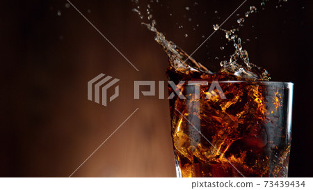 Cola drink splashing out of glass Cola drink splashing out of glass 73439434