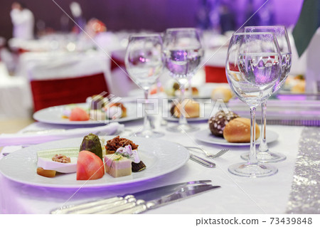 Festive round table setting in a prestigious restaurant for dinner. Banquet decoration with white and red Festive round table setting in a prestigious restaurant for dinner. Banquet decoration with white and red 73439848