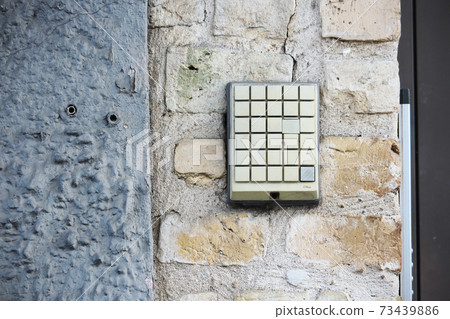 Square entrance old broken intercom buttons on brick wall Square entrance old broken intercom buttons on brick wall 73439886