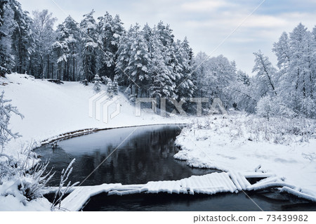 Beautiful snowy winter landscape of forest river with bridge, Belarus. Beautiful snowy winter landscape of forest river with bridge, Belarus. 73439982
