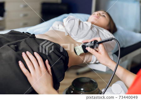 Extracorporeal shockwave therapy in urology. Cropped shot of lying woman patient, having ultrasound to determine kidney stones position before the lithotripsy procedure. 73440049