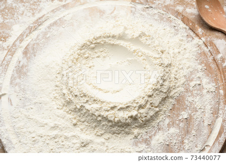 white wheat flour heaped on a round wooden board white wheat flour heaped on a round wooden board 73440077