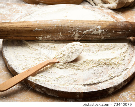 white wheat flour in a wooden spoon, top view 73440079