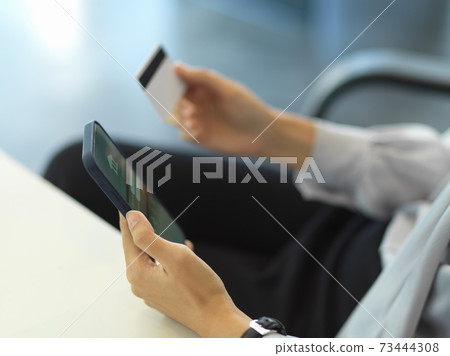 Businesswoman hand holding credit card while online paying on smartphone 73444308
