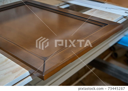 Wooden cabinet door in workshop. Lacquered. Wooden furniture manufacturing process 73445287
