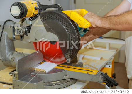 Man cut the wooden molding with circular saw Man cut the wooden molding with circular saw 73445790