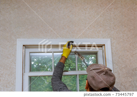The process of removing an old wooden window from an opening in a house before replacing it with a new one. The process of removing an old wooden window from an opening in a house before replacing it with a new one. 73445797