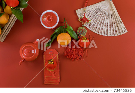Happy Lunar Chinese New Year celebrations with ceremony tea set, lump red envelopes Packet Ang Pau on mandarin oranges a red background Happy Lunar Chinese New Year celebrations with ceremony tea set, lump red envelopes Packet Ang Pau on mandarin oranges a red background 73445826