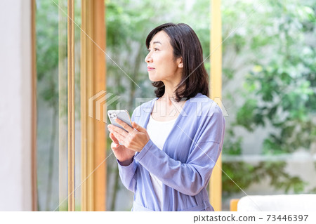 在客廳裡操作智能手機的中年女人 73446397
