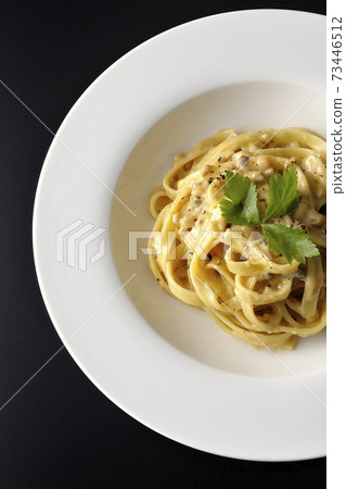 Photographed flat pasta with truffle cream with trefoil on a black background (overhead view) Photographed flat pasta with truffle cream with trefoil on a black background (overhead view) 73446512