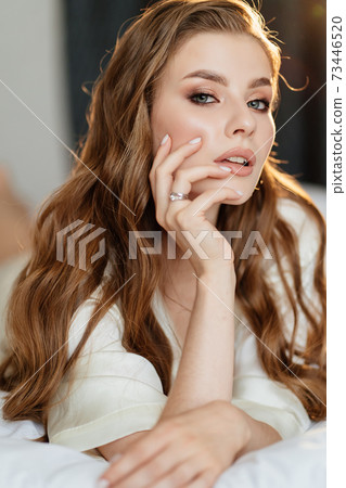 close up. portrait of beautiful woman with long hair in robe lying on bed. close up. portrait of beautiful woman with long hair in robe lying on bed. 73446520