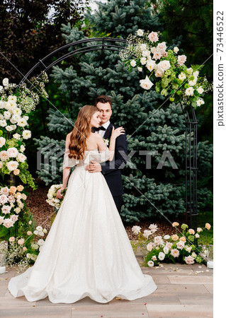 outdoor wedding ceremony in an arch of living flowers.Beautiful couple newlyweds outdoor wedding ceremony in an arch of living flowers.Beautiful couple newlyweds 73446522