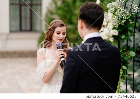 wedding ceremony in arch of living flowers. bride says wedding vow and cry wedding ceremony in arch of living flowers. bride says wedding vow and cry 73446625