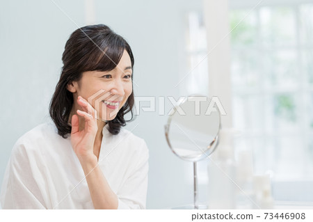 Middle woman smiling looking in the mirror 73446908