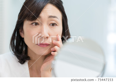 Middle woman who cares about wrinkles on the face 73447153