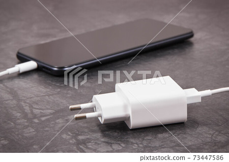 Smartphone with connected plug of charger. Telephone charging 73447586
