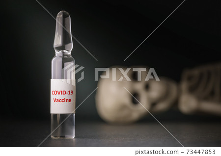 Ampoule with a vaccine against coronavirus and a toy human skeleton, close-up. Concept of drug efficacy against the COVID-19 pandemic 73447853