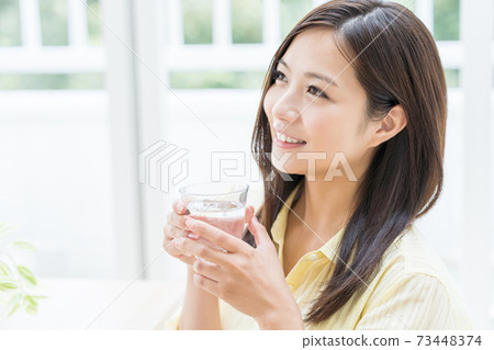 Young woman drinking water in the room Young woman drinking water in the room 73448374