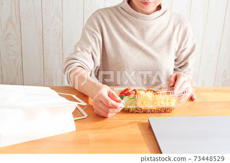 一個女人在電腦前吃外賣午餐 一個女人在電腦前吃外賣午餐 73448529