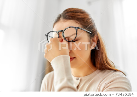 tired asian woman with glasses rubbing nose bridge 73450194