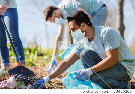volunteers with garbage bags cleaning park area 73450209