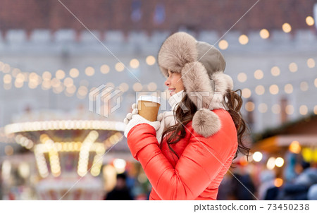 happy woman drinking coffee at christmas market 73450238