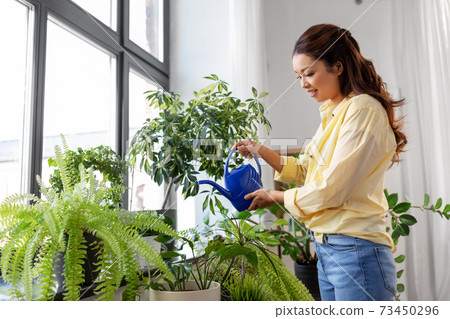 happy asian woman watering plants at home 73450296