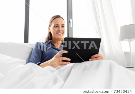 young woman with tablet pc in bed at home bedroom 73450434